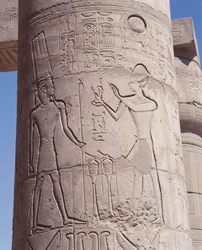 Relief of pharaoh holding goddess of justice Maat before Amon on pillar