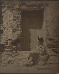 Woman Seated Before Deteriorating Building
