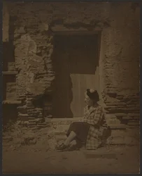 Woman Seated Before Deteriorating Building