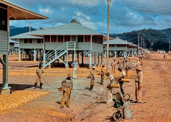 Men spray DDT pesticide insecticide to control insects around newly constructed barracks
