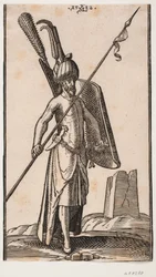 Standing soldier with curved shield in left hand and spear in right hand; sword at his left side, a dagger stuck in the belt at his left side; in the background to the right, the ruin of an obelisk or a tower with a square base