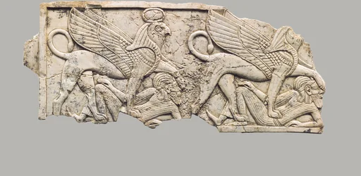 Furniture plaque carved in relief with two falcon-headed sphinxes trampling captives