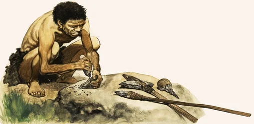 A Stone Age man making a weapon