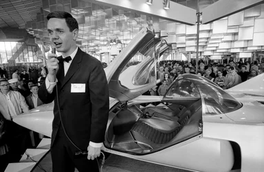 Announcer with futuristic Firebird III experimental gas turbine automobile at General Motors exhibit