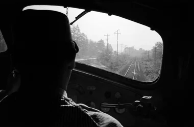 View of tracks from the cab of a diesel locomotive with the engineer, Pacific Northwest