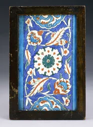 An Iznik Border Tile, with a Central Flowerhead between Scrolling Palmette and Leafy Vine