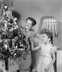 Woman and girl decorating a Christmas tree, c 1948