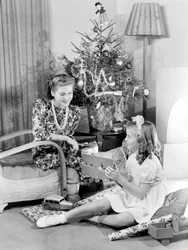 Woman and girl looking at Christmas presents, c 1950
