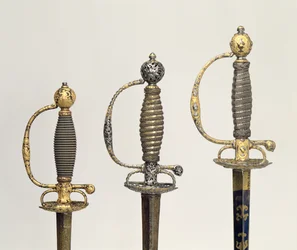 Hilts of three French swords: one of steel, blued and overlaid with designs in chased gold, c.1730; one of steel pierced and chiselled and the ground of matted gold, c.1760; one of chiselled steel