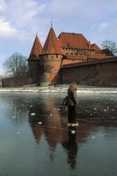 Side profile of a man standing on a frozen river in front of a castle, Nogat River, Malbork Castle, Malbork, Pomorskie Province, Poland