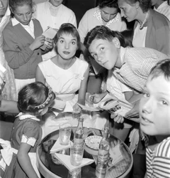 THE ACTRESS AND FASHION MODEL ELSA MARTINELLI AT THE XVIII INTERNATIONAL FILM FESTIVAL AT THE VENICE LIDO (she signs autographs for young fans. On the table is a bottle of Schweppes) - 1957