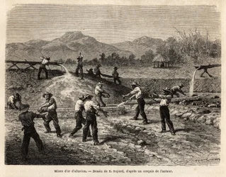 An alluvion gold mine, open air in Colombia, by means of pumps, a stream of water brings the auriferous sludge back to the work site, the tools of the miners are of the utmost simplicity, iron bars and a pool of rocks in which heavy particles and golden pe