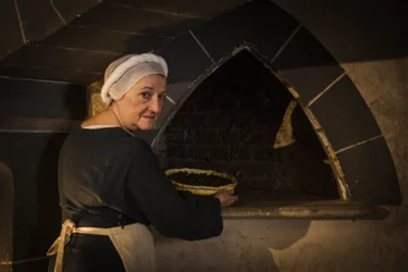 Historical reenactment: Maid putting cake in oven of kitchen of castle