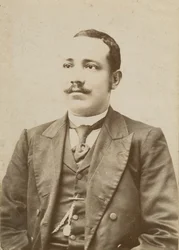 Photograph of a man wearing a dark colored suit with a pocket watch in his vest