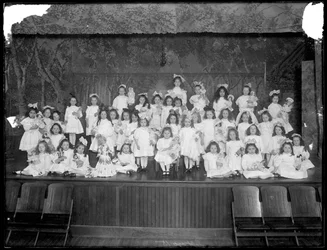 Group of Little Girls Posed on a Small Stage Holding Dolls, Probably the Roman Catholic Orphan Asylum, Kingsbridge, Bronx, c.1911
