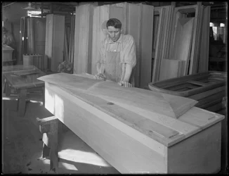 Worker fitting a piece of a casket lid, Oneida, New York, April 3, 1916