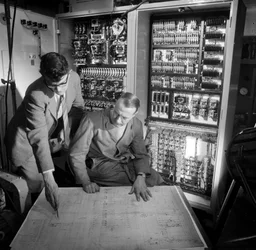 Engineers Discuss Plans in Front of the Electronic Control Panel They Have Built